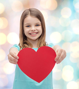 Smiling female student holds up a paper heart