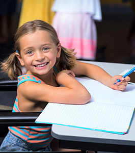 Smiling female student holds a colored pencil on top of a notebook