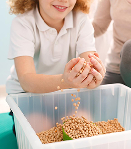 Student scoops up marbles with her hands