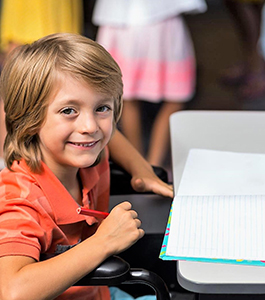 Smiling male student holds a colored pencil near a notebook