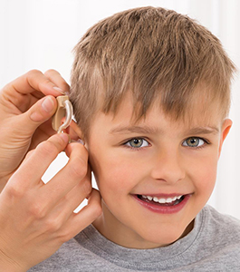 Smiling male student has a hearing aid put on him