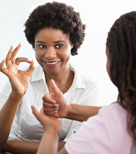 Teacher holds up an a-okay sign and a student gives a thumbs up