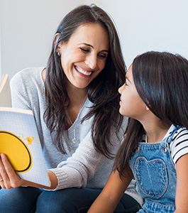 Smiling student reads with a smiling woman